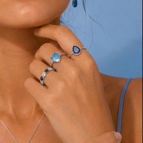 Jewelry set including necklace, ring, and earrings with blue gemstones on a blue background