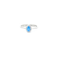 A sterling silver ring with a teardrop-shaped aquamarine cubic zirconia centerpiece, set in a smaller circular frame with smaller clear stones around it.