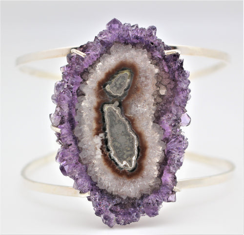 A sterling silver cuff bracelet with a central amethyst geode design.