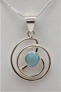 A Larimar Pendant set in a 925 Sterling Silver mounting, with a circular silver frame and a blue Larimar stone in the center.